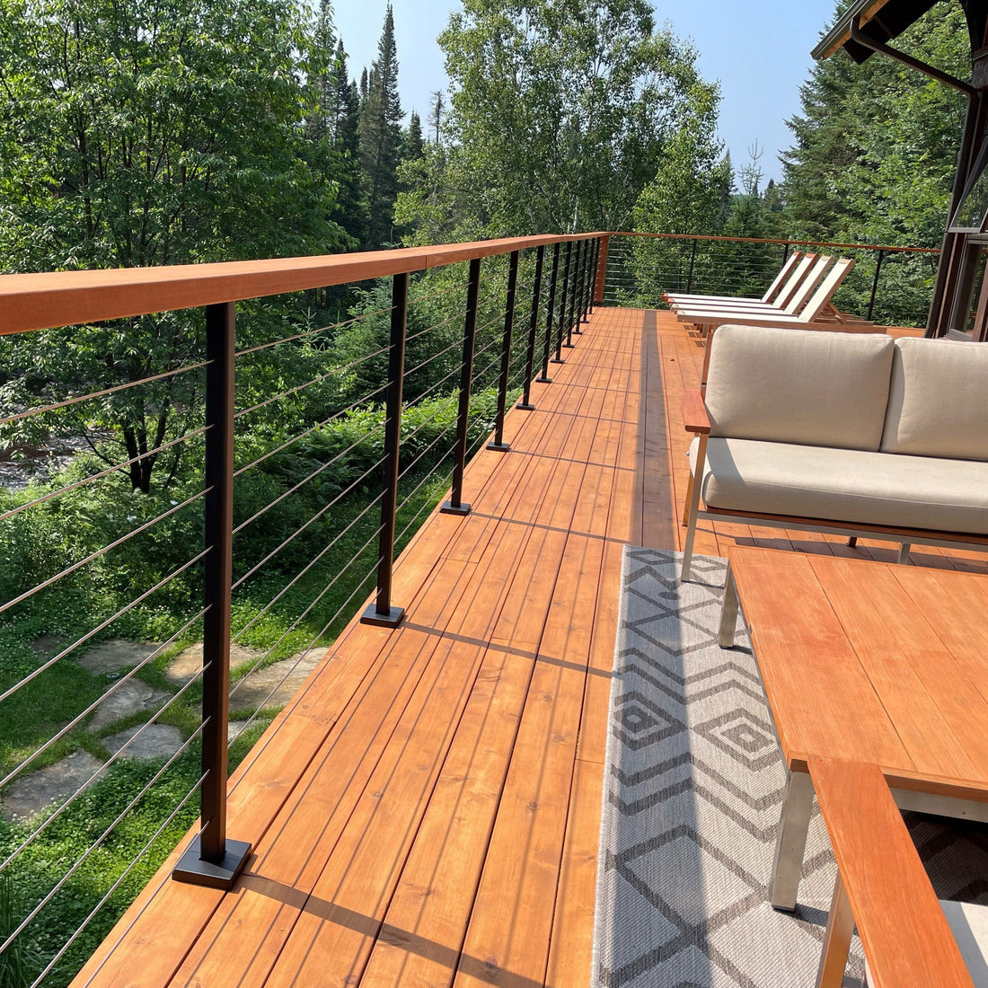 Wooden deck with outdoor furniture and railing overlooking a forest
